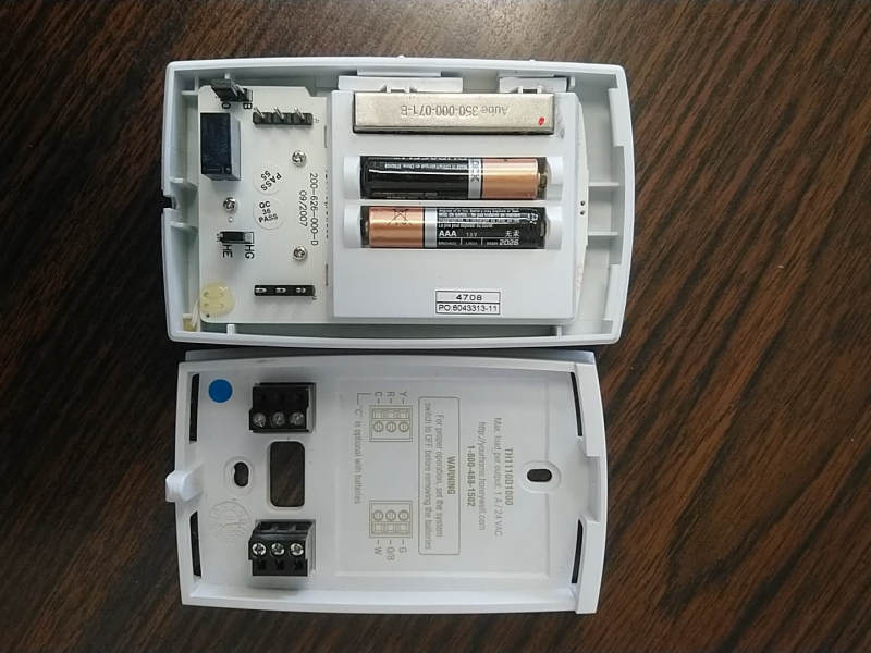 Thermostat open with batteries exposed.