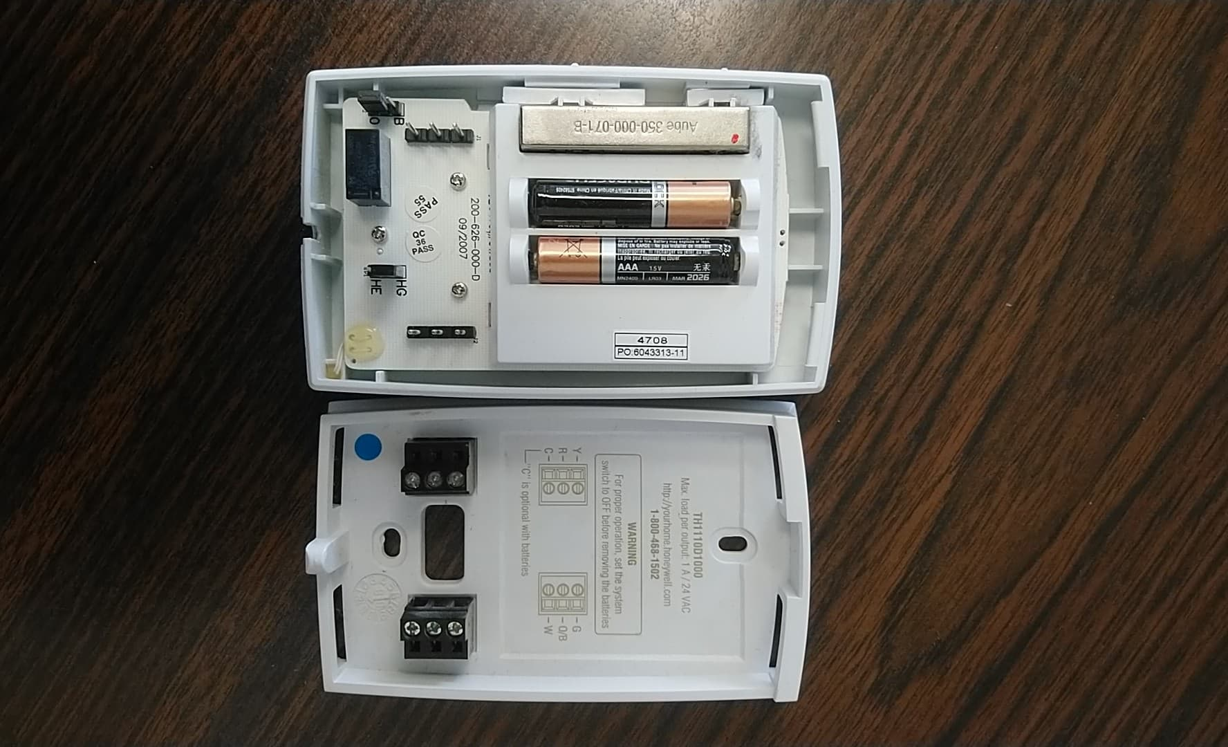 Thermostat open with batteries exposed.